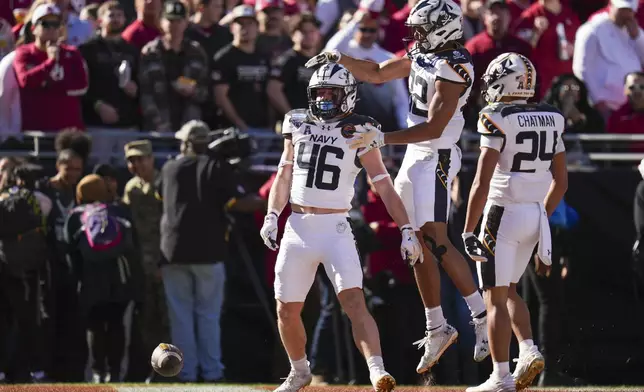 Navy fullback Alex Tecza, (46) celebrates his touchdown run with running backs Eli Heidenreich (22) and Brandon Chatman (24) during the first half of the Armed Forces Bowl NCAA college football game against Oklahoma, Friday, Dec. 27, 2024, in Fort Worth, Texas. (AP Photo/Julio Cortez)