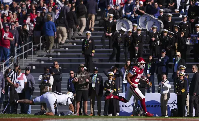 Oklahoma running back Gavin Sawchuk (27) laves behind Navy safety Rayuan Lane III on his way to a touchdown during the first half of the Armed Forces Bowl NCAA college football game, Friday, Dec. 27, 2024, in Fort Worth, Texas. (AP Photo/Julio Cortez)