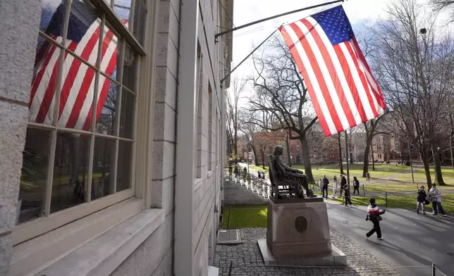 People walk past the John Harvard statue in Harvard Yard, Tuesday, Dec. 17, 2024, on the campus of Harvard University in Cambridge, Mass. (AP Photo/Steven Senne)