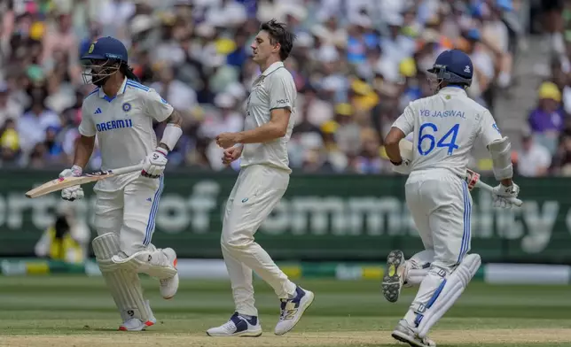 Australia's captain Pat Cummins, center, looks on as India's KL Rahul, left, and Yashasvi Jaiswal run between the wickets to score during play on the second day of the fourth cricket test between Australia and India at the Melbourne Cricket Ground, Melbourne, Australia, Friday, Dec. 27, 2024. (AP Photo/Asanka Brendon Ratnayake)