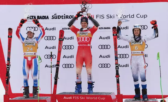 Switzerland's Marco Odermatt, center, winner of an alpine ski, men's World Cup giant slalom, celebrates with second-placed France's Leo Anguenot, left, and third-placed Norway's Alexander Steen Olsen, in Alta Badia, Italy, Sunday, Dec. 22, 2024. (AP Photo/Alessandro Trovati)