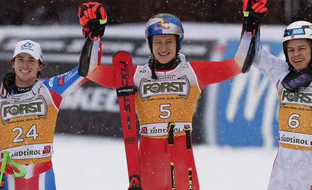 Switzerland's Marco Odermatt, center, winner of an alpine ski, men's World Cup giant slalom, celebrates with second-placed France's Leo Anguenot, left, and third-placed Norway's Alexander Steen Olsen, in Alta Badia, Italy, Sunday, Dec. 22, 2024. (AP Photo/Alessandro Trovati)