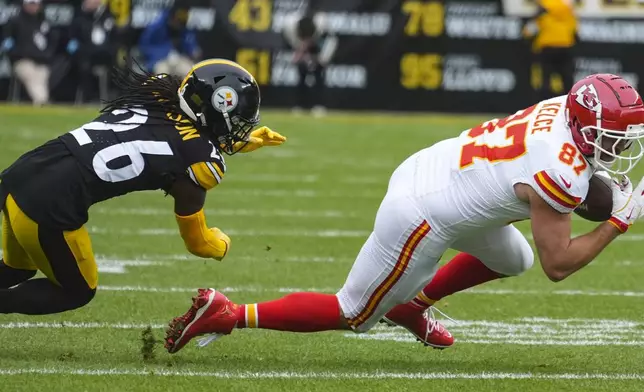 Kansas City Chiefs tight end Travis Kelce (87) makes the catch against Kansas City Chiefs safety Deon Bush (26) during the first half of an NFL football game, Wednesday, Dec. 25, 2024, in Pittsburgh. (AP Photo/Gene J. Puskar)