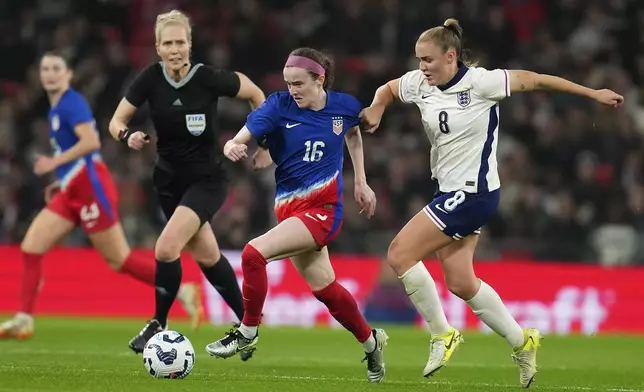 United States' Rose Lavelle and England's Georgia Stanwaychallenge for the ball whilst referee Lina Lehtovaara looks on during the International friendly women soccer match between England and United States at Wembley stadium in London, Saturday, Nov. 30, 2024. (AP Photo/Kirsty Wigglesworth)