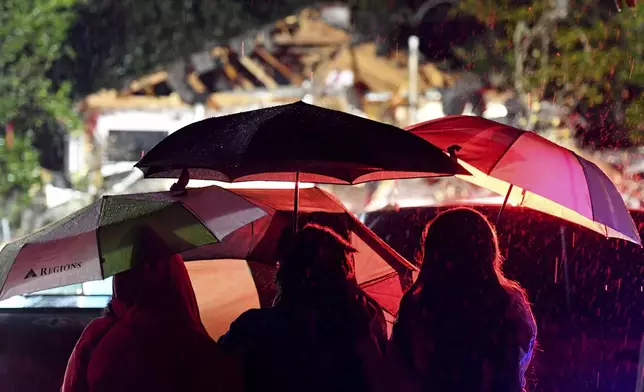 Bystanders watch as first responders work to free a victim after a tree fell on a house in Natchez, Miss., Saturday, Dec. 28, 2024. (Thomas Graning/The Natchez Democrat via AP)