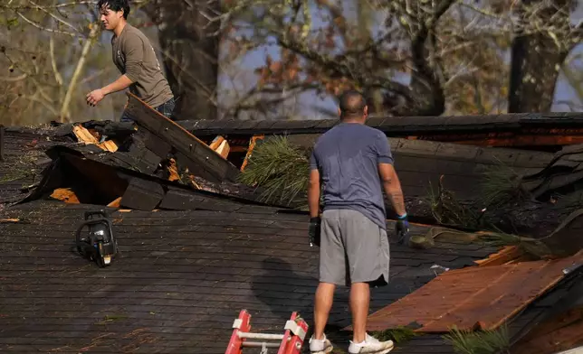 Men work to remove debris and cover a damaged roof after strong thunderstorms pass through the Greater Houston region, Saturday, Dec. 28, 2024, in Porter Heights. (Jason Fochtman/Houston Chronicle via AP)