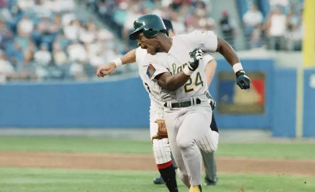 FILE - Oakland Athletics Rickey Henderson (24) keeps just ahead of Chicago White Sox shortstop Ozzie Guillen during a rundown between first and second base during the third inning of a baseball game June 14, 1994, in Chicago. (AP Photo/Fred Jewell, File)