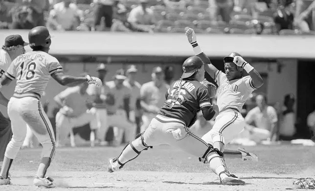 FILE - Oakland Athletics' Rickey Henderson, right, slides home safely past Cleveland Indians catcher Jerry Willard to score from third base on a hit by Davey Lopes during the seventh inning of a baseball game in Oakland, Calif., June 14, 1984. (AP Photo/Jeff Reinking, File)