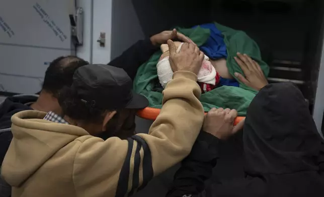 Relatives of Palestinian Imran Haroun, touch his body at the hospital morgue after he was killed during a military operation in the Tulkarem refugee camp near the West Bank city of Tulkarem, Wednesday, Dec. 25, 2024. (AP Photo/Majdi Mohammed)