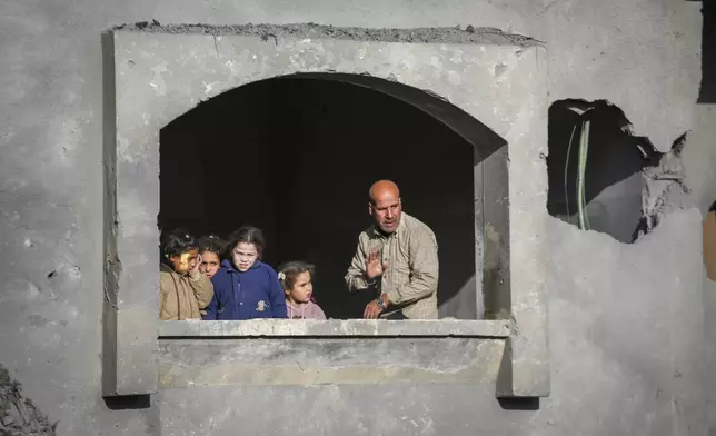 Neighbours watch the funeral procession of the victims of an Israeli strike on a home late Saturday, in Deir al-Balah, central Gaza Strip, Sunday, Dec. 22, 2024. At least eight people were killed according to the hospital which received the bodies.(AP Photo/Abdel Kareem Hana)