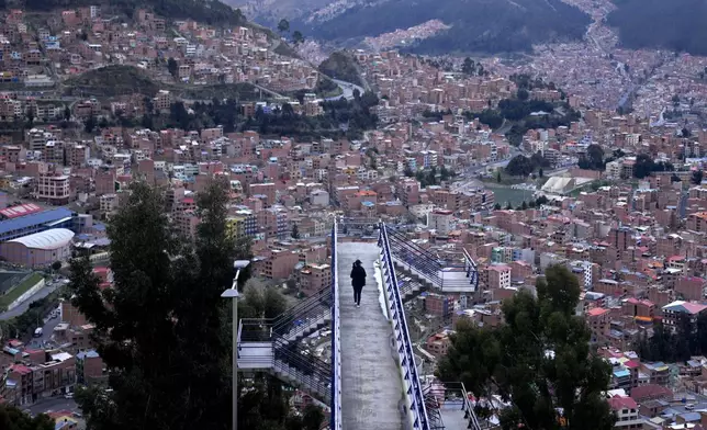 FILE - A woman walks across a pedestrian bridge in La Paz, Bolivia, Nov. 27, 2024. (AP Photo/Juan Karita, File)