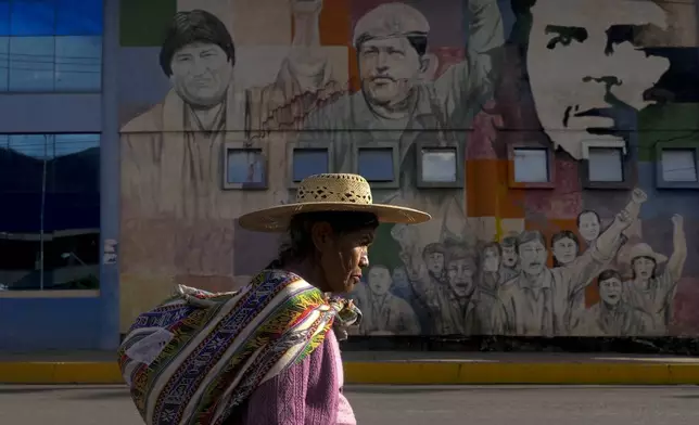 FILE - A woman walks past a mural featuring socialist leaders, from left; former Bolivian President Evo Morales, late Venezuelan President Hugo Chavez and revolutionary Ernesto "Che: Guevara, at the bus terminal in Sacaba, Bolivia, Nov. 20, 2024. (AP Photo/Juan Karita, File)