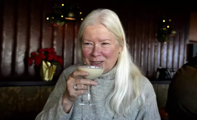 Laurie Kenny takes a sip of eggnog at Scoma's Restaurant in San Francisco on Dec. 10, 2024. The eggnog is prepared 11 months in advance. (AP Photo/Terry Chea)