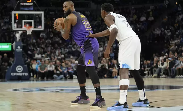 Los Angeles Lakers forward LeBron James (23) handles the ball as Minnesota Timberwolves guard Anthony Edwards (5) defends during the first half of an NBA basketball game, Monday, Dec. 2, 2024, in Minneapolis. (AP Photo/Abbie Parr)