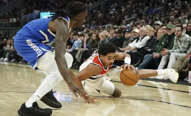 Washington Wizards' Jordan Poole, right, controls the ball as he falls to the floor against Milwaukee Bucks' Taurean Prince during the first half of an NBA basketball game Saturday, Nov. 30, 2024, in Milwaukee. (AP Photo/Aaron Gash)