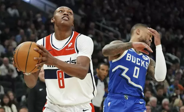 Washington Wizards' Carlton Carrington (8) drives to the basket past Milwaukee Bucks' Damian Lillard (0) during the first half of an NBA basketball game Saturday, Nov. 30, 2024, in Milwaukee. (AP Photo/Aaron Gash)