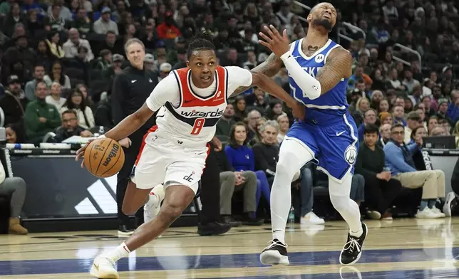 Washington Wizards' Carlton Carrington (8) drives to the basket past Milwaukee Bucks' Damian Lillard during the first half of an NBA basketball game Saturday, Nov. 30, 2024, in Milwaukee. (AP Photo/Aaron Gash)