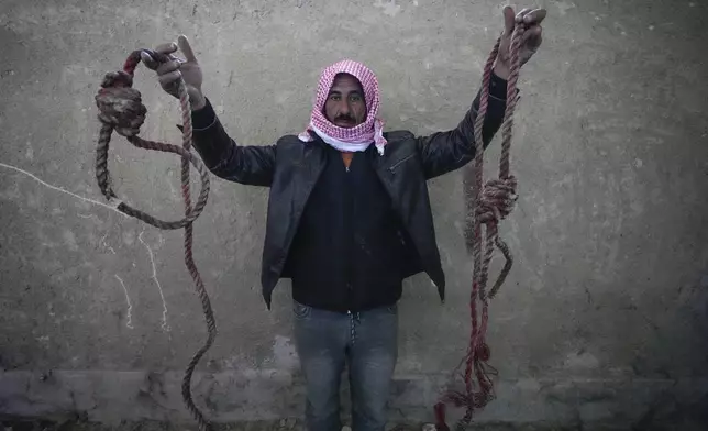 FILE - A man holds two ropes tied in the shape of nooses, found in the infamous Saydnaya military prison, just north of Damascus, Syria, Monday, Dec. 9, 2024. (AP Photo/Hussein Malla, File)