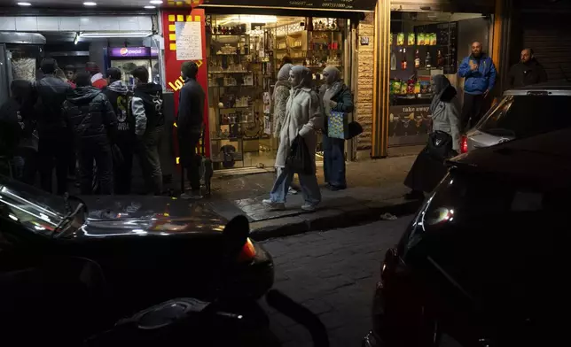 People walk past shops on a street in the Bab Touma neighborhood of the Old City of Damascus, Syria, Saturday, Dec. 14, 2024. (AP Photo/Leo Correa)