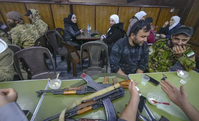 FILE - Opposition fighters sit in a restaurant at the Al-Hamidiyeh market inside the old walled city of Damascus, Syria, Tuesday, Dec. 10, 2024. (AP Photo/Hussein Malla, File)