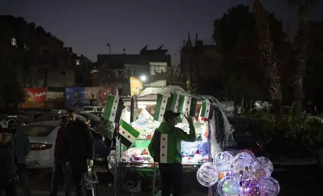 A street vendor flashes a victory sign in the Bab Touma neighborhood in the Old City of Damascus, Syria, Saturday, Dec. 14, 2024. (AP Photo/Leo Correa)