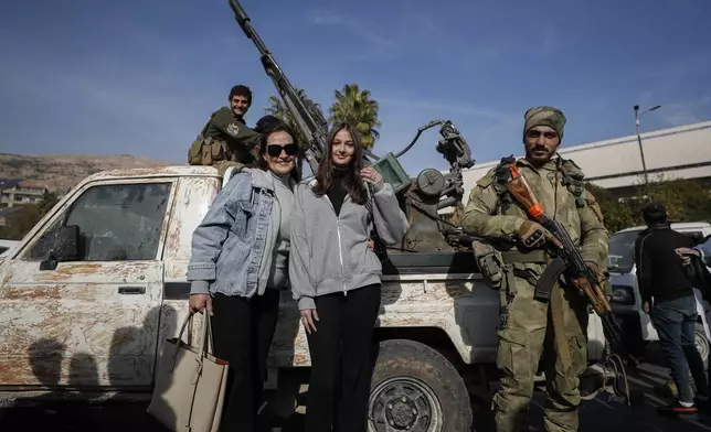 FILE - Women pose for a photograph with opposition fighters in Damascus, Syria, Tuesday, Dec. 10, 2024. (AP Photo/Omar Sanadiki, File)