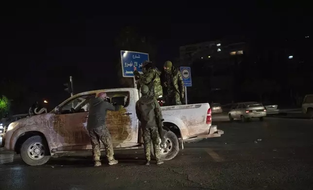 Syrian fighters stand on a street at the central square in Damascus, Syria, Saturday, Dec. 14, 2024. (AP Photo/Leo Correa)