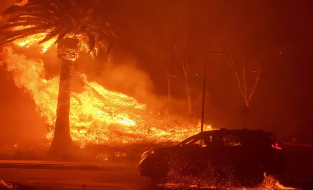 A car drives past flames from the Franklin Fire at Pepperdine University in Malibu, Calif., Tuesday, Dec. 10, 2024. (AP Photo/Eric Thayer)