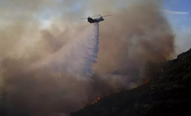 Water is dropped by helicopter onto the Franklin Fire, Tuesday, Dec. 10, 2024, in Malibu, Calif. (AP Photo/Eric Thayer)