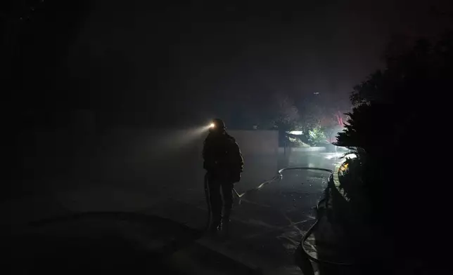 A firefighter carries a water hose while tackling the Franklin Fire in Malibu, Calif., Tuesday, Dec. 10, 2024. (AP Photo/Jae C. Hong)