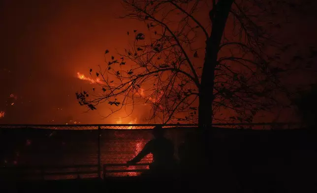 Two firefighters watch the Franklin Fire as it approaches a building in Malibu, Calif., Tuesday, Dec. 10, 2024. (AP Photo/Jae C. Hong)