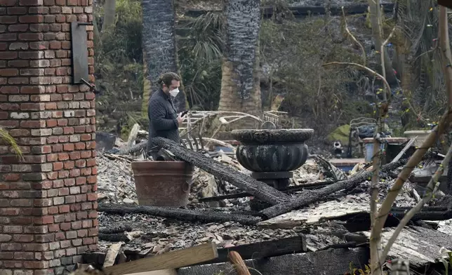 A resident sifts through their fire-damage property after the Franklin Fire swept through, Wednesday, Dec. 11, 2024, in Malibu, Calif. (AP Photo/Damian Dovarganes)