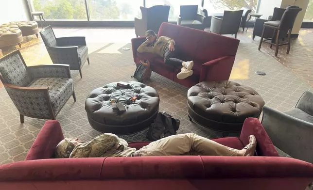 Students sleep on couches on the Pepperdine University campus, where a makeshift shelter was set up as the Franklin Fire closed in Tuesday, Dec. 10, 2024, in Malibu, Calif. (AP Photo/Damian Dovarganes)