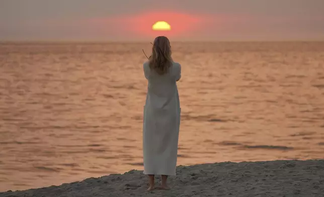 Screen writer and actress Sarah Newcome expresses her gratitude to God during sunset as a plume of smoke from the Franklin Fire rises over the ocean Tuesday, Dec. 10, 2024, in Malibu, Calif. (AP Photo/Damian Dovarganes)