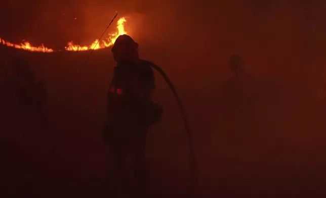 Two firefighters are engulfed in smoke from the Franklin Fire in Malibu, Calif., Tuesday, Dec. 10, 2024. (AP Photo/Jae C. Hong)