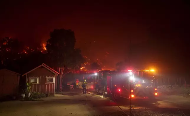 Firefighters protect a structure as the Franklin Fire approaches in Malibu, Calif., Tuesday, Dec. 10, 2024. (AP Photo/Eric Thayer)