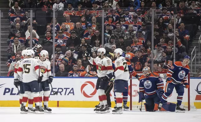 Florida Panthers players celebrate after a goal as Edmonton Oilers goalie Stuart Skinner (74) and Ty Emberson (49) look on during second-period NHL hockey game action in Edmonton, Alberta, Monday, Dec. 16, 2024. (Jason Franson/The Canadian Press via AP)