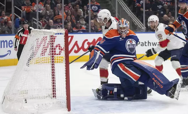 Florida Panthers' Matthew Tkachuk, center top, scores against Edmonton Oilers goalie Stuart Skinner, center bottom, during first-period NHL hockey game action in Edmonton, Alberta, Monday, Dec. 16, 2024. (Jason Franson/The Canadian Press via AP)