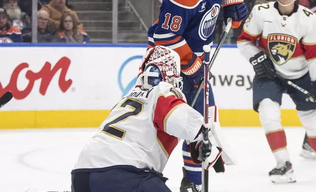 Florida Panthers goalie Sergei Bobrovsky, left, tries to make a save as Edmonton Oilers' Zach Hyman (18) is hit in the face with the shot during second-period NHL hockey game action in Edmonton, Alberta, Monday, Dec. 16, 2024. (Jason Franson/The Canadian Press via AP)