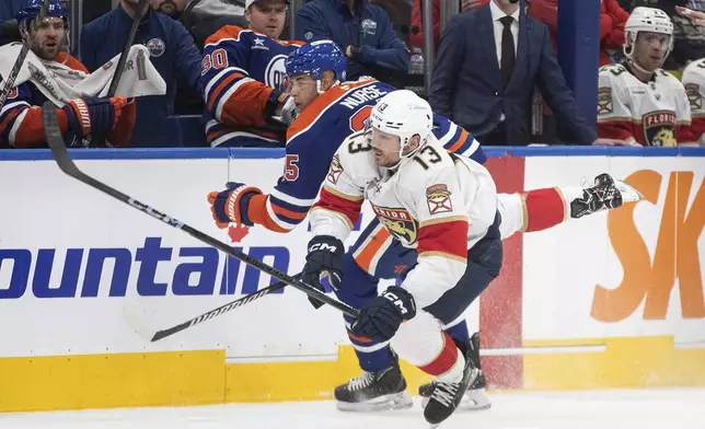 Florida Panthers Sam Reinhart (13) is checked by Edmonton Oilers' Darnell Nurse, left, during first-period NHL hockey game action in Edmonton, Alberta, Monday, Dec. 16, 2024. (Jason Franson/The Canadian Press via AP)