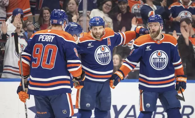 Edmonton Oilers' Corey Perry (90), Ryan Nugent-Hopkins (93), Leon Draisaitl (29) and Mattias Ekholm (14) celebrate after a goal against the Florida Panthers during second-period NHL hockey game action in Edmonton, Alberta, Monday, Dec. 16, 2024. (Jason Franson/The Canadian Press via AP)