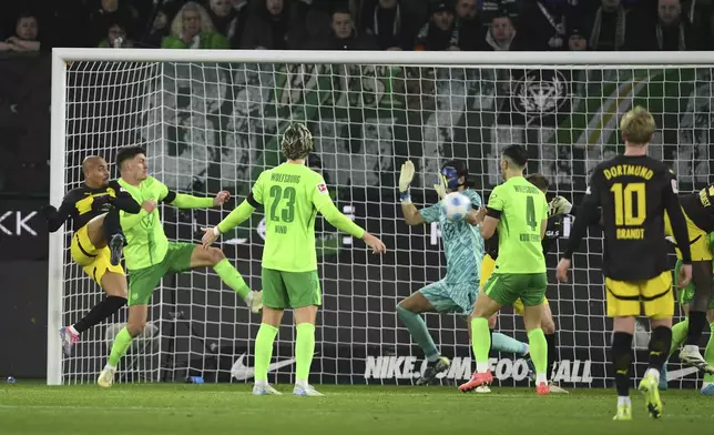 Dortmund's Donyell Malen, left, scores their side's first goal of the game during the Bundesliga soccer match between VfL Wolfsburg and Borussia Dortmund, in Wolfsburg, Germany, Sunday Dec. 22, 2024. (Swen Pförtner/dpa via AP)