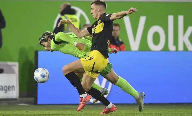 Dortmund's Nico Schlotterbeck, right, and Wolfsburg's Jonas Wind fight for the ball during the Bundesliga soccer match between VfL Wolfsburg and Borussia Dortmund, in Wolfsburg, Germany, Sunday Dec. 22, 2024. (Swen Pförtner/dpa via AP)