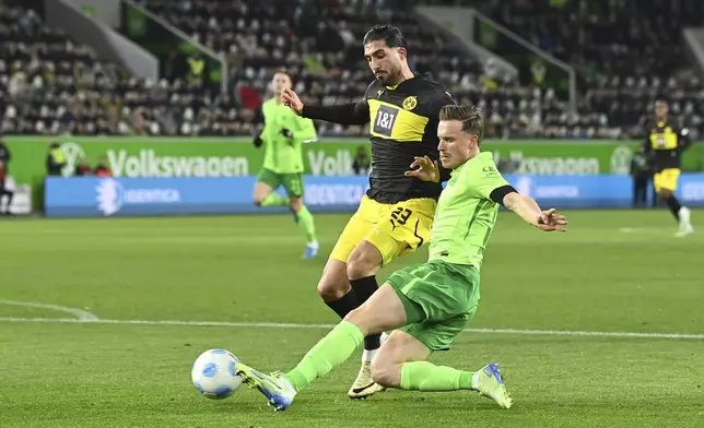 Dortmund's Emre Can, left, and Wolfsburg's Yannick Gerhardt fight for the ball during the Bundesliga soccer match between VfL Wolfsburg and Borussia Dortmund, in Wolfsburg, Germany, Sunday Dec. 22, 2024. (Swen Pförtner/dpa via AP)