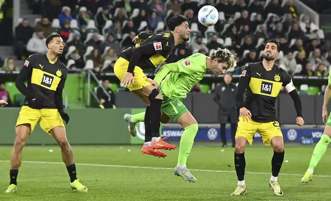 Dortmund's Emre Can, left, and Wolfsburg's Jonas Wind fight for the ball during the Bundesliga soccer match between VfL Wolfsburg and Borussia Dortmund, in Wolfsburg, Germany, Sunday Dec. 22, 2024. (Swen Pförtner/dpa via AP)