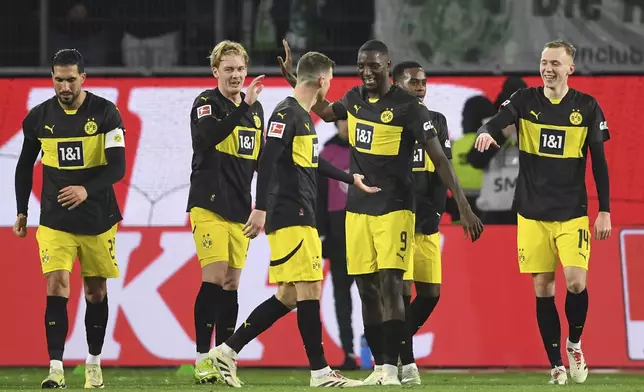 Dortmund's Julian Brandt, centre applauds Dortmund's Serhou Guirassy after his goal during the Bundesliga soccer match between VfL Wolfsburg and Borussia Dortmund, in Wolfsburg, Germany, Sunday Dec. 22, 2024. (Swen Pförtner/dpa via AP)