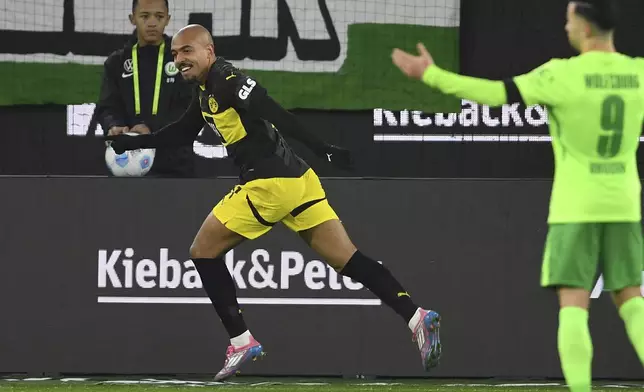 Dortmund's Donyell Malen, left, celebrates after scoring their side's first goal of the game during the Bundesliga soccer match between VfL Wolfsburg and Borussia Dortmund, in Wolfsburg, Germany, Sunday Dec. 22, 2024. (Swen Pförtner/dpa via AP)