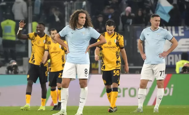 Lazio's Matteo Guendouzi, centre, and Lazio's Adam Marusic, right, react as Inter Milan's Marcus Thuram, left on the background, celebrates after scoring his side's sixth goal during the Italian Serie A soccer match between Lazio and Inter at Rome's Olympic Stadium, Rome, Italy, Monday, Dec. 16, 2024. (AP Photo/Gregorio Borgia)