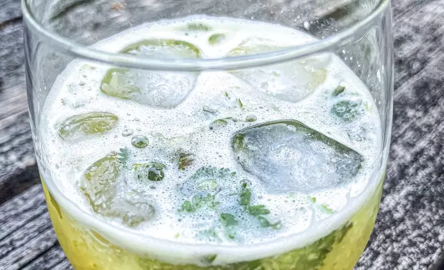 This 2021 image shows a Tepache mocktail made with cilantro simple syrup and fresh cilantro. (Suzanne Podhaizer via AP)