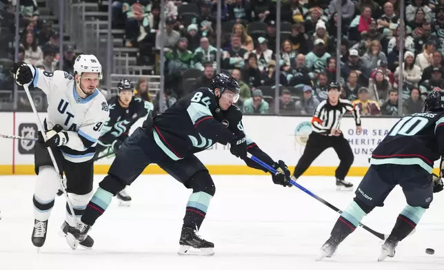 Seattle Kraken right wing Kaapo Kakko (84) passes the puck away from Utah Hockey Club defenseman Mikhail Sergachev, left, during the second period of an NHL hockey game Monday, Dec. 30, 2024, in Seattle. (AP Photo/Lindsey Wasson)